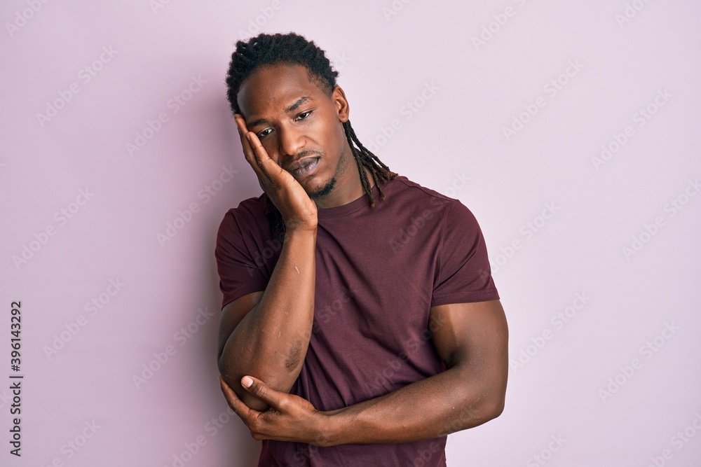 African american man with braids wearing casual clothes thinking looking tired and bored with depression problems with crossed arms. African american man with braids wearing casual clothes thinking looking tired and bored with depression problems with crossed arms.