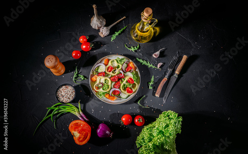 Healthy vegetable salad of fresh tomato, green leaves mix and vegetables. Top view on dark bacground. Diet menu