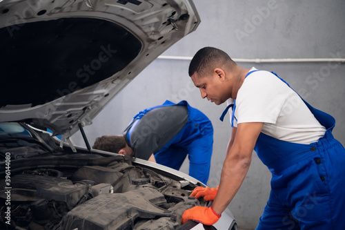 Two experienced techies repair a broken car engine