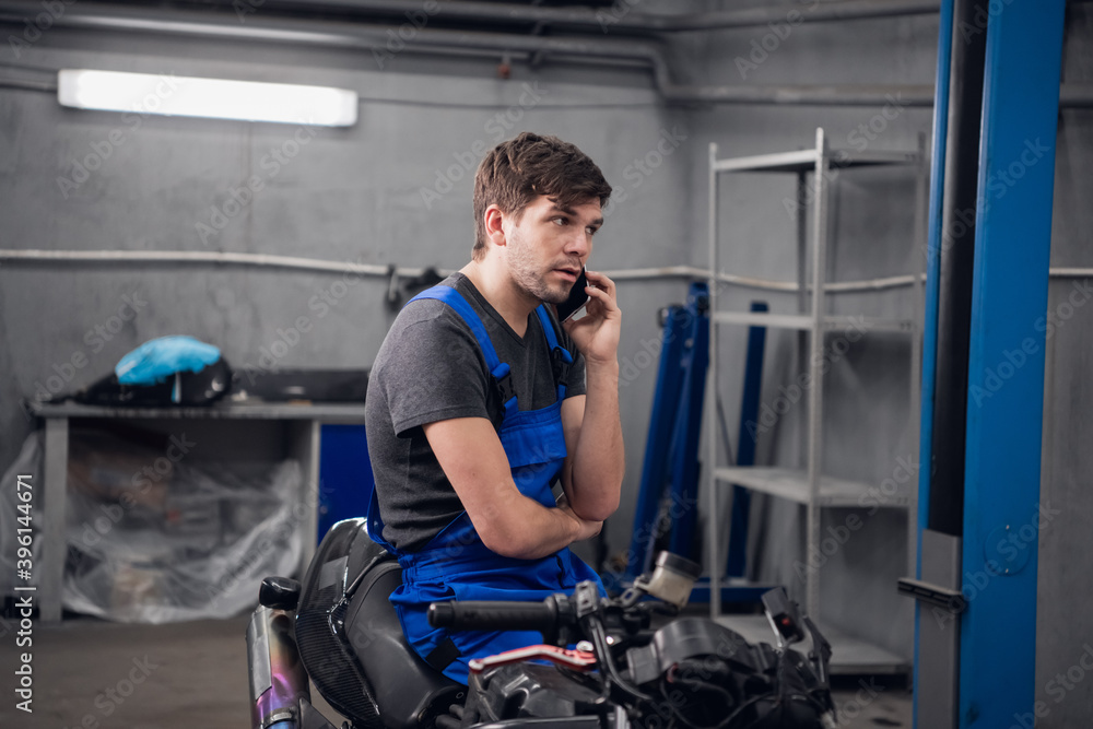 A machinist talking to a client on the phone about a motorcycle A machinist talking to a client on the phone about a motorcycle