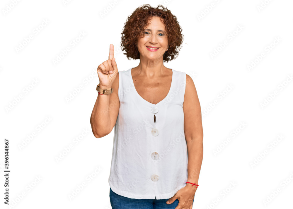 Beautiful middle age mature woman wearing casual white shirt showing and pointing up with finger number one while smiling confident and happy. Beautiful middle age mature woman wearing casual white shirt showing and pointing up with finger number one while smiling confident and happy.
