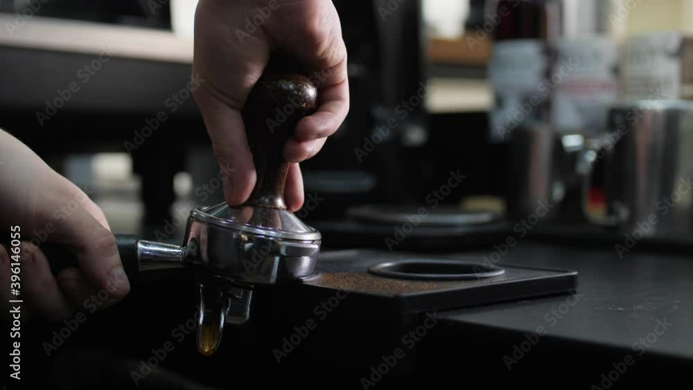 Barista uses tamper press ground coffee in comfortable cafe Barista uses tamper press ground coffee in comfortable cafe