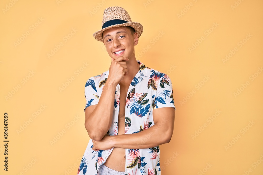 Young hispanic boy wearing summer hat smiling looking confident at the camera with crossed arms and hand on chin. thinking positive. Young hispanic boy wearing summer hat smiling looking confident at the camera with crossed arms and hand on chin. thinking positive.