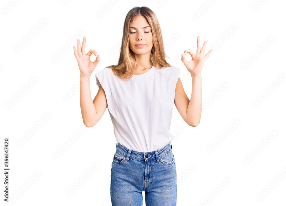 Beautiful caucasian woman with blonde hair wearing casual white tshirt relax and smiling with eyes closed doing meditation gesture with fingers. yoga concept. Beautiful caucasian woman with blonde hair wearing casual white tshirt relax and smiling with eyes closed doing meditation gesture with fingers. yoga concept.
