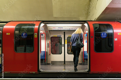 LONDON, ENGLAND - OCTOBER 23, 2020:  A woman embarking upon a Central Line train on the London Underground Tube platform at Holborn Station wearing a face mask during the COVID-19 pandemic -041