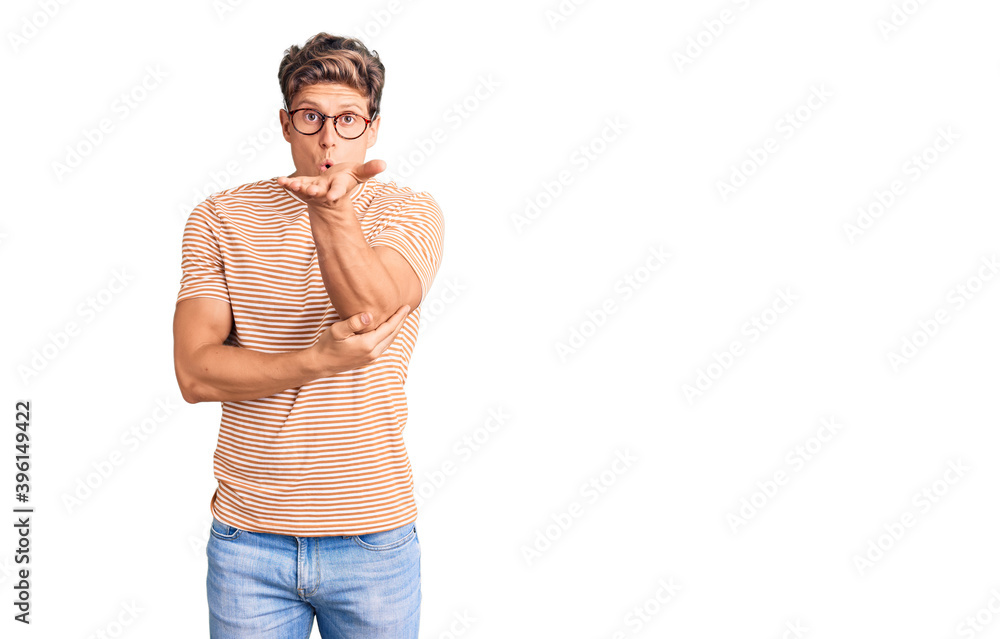 Fototapeta premium Young handsome man wearing casual clothes and glasses looking at the camera blowing a kiss with hand on air being lovely and sexy. love expression.