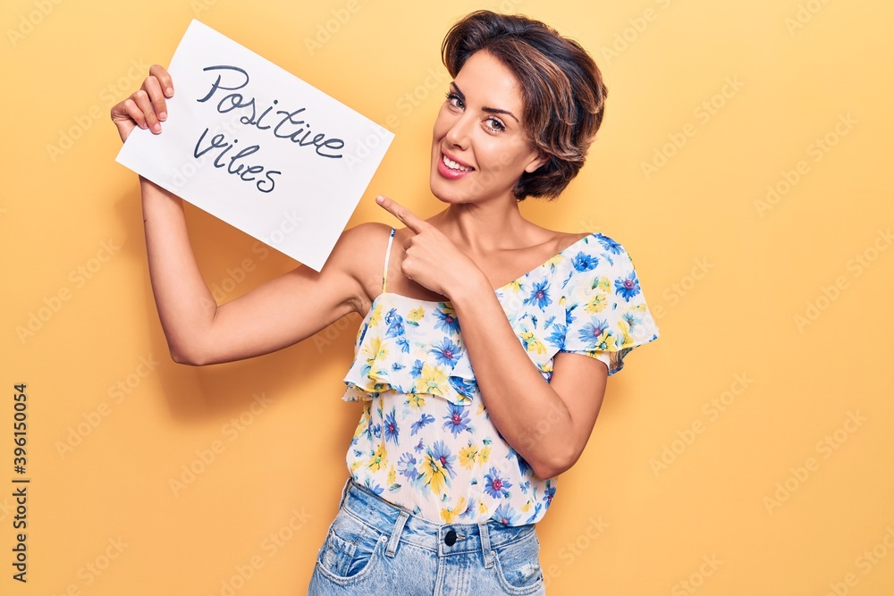 Young beautiful woman holding positive vibes banner smiling happy pointing with hand and finger Young beautiful woman holding positive vibes banner smiling happy pointing with hand and finger