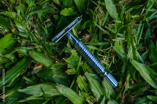 Reusable steel double edged eco-friendly safety razor on grass background. Zero waste sustainable plastic free lifestyle