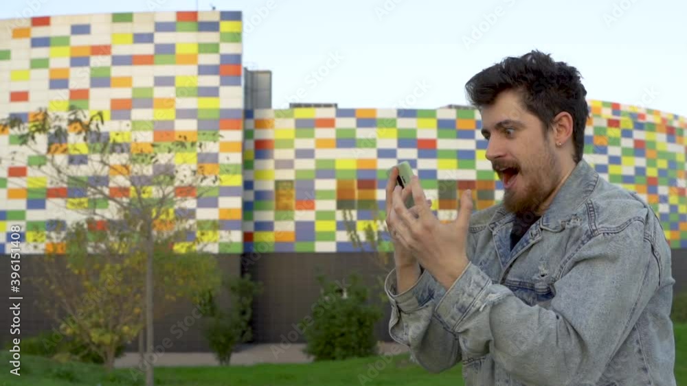 Young man looks at the phone and celebrates in a big way a news or result Young man looks at the phone and celebrates in a big way a news or result