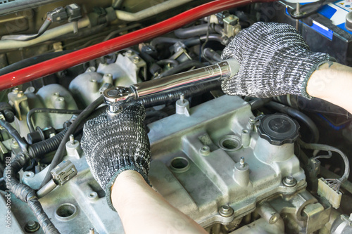 Auto mechanic use torque wrench to adjust spark plug, Car maintenance service. photo