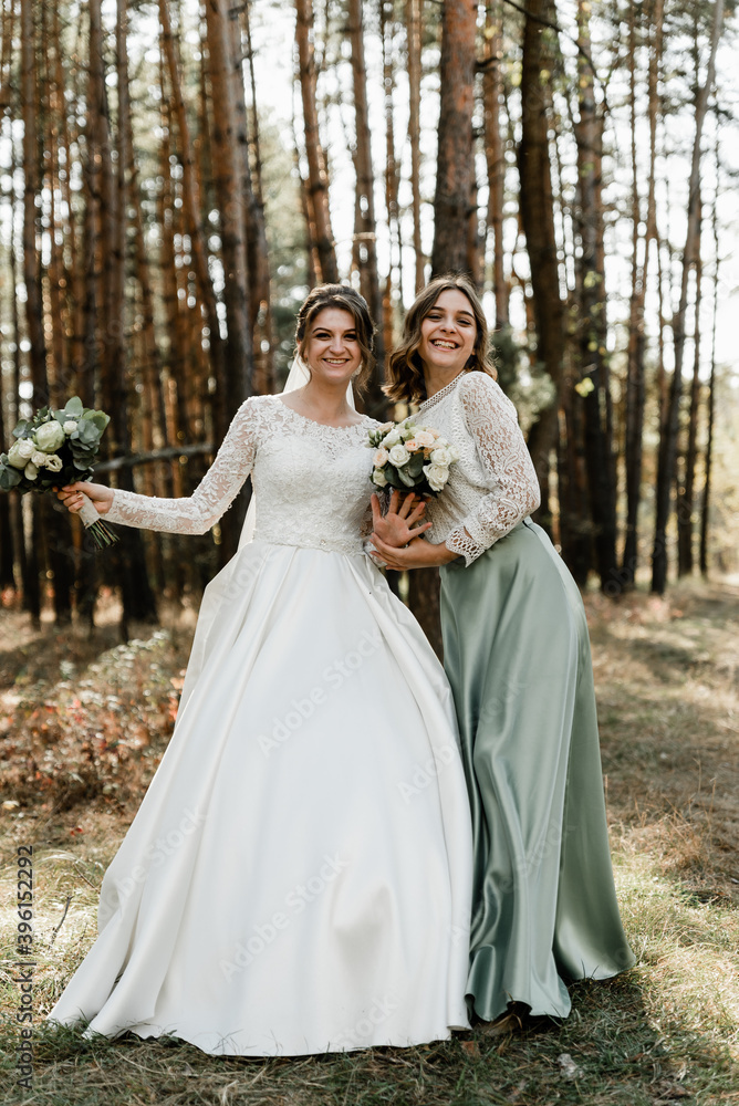Tender bride with smiling bridesmaids dressed in long elegant dresses,bridesmaids with happy bride on wedding day. wedding bouquets are held by girlfriends, wedding day,