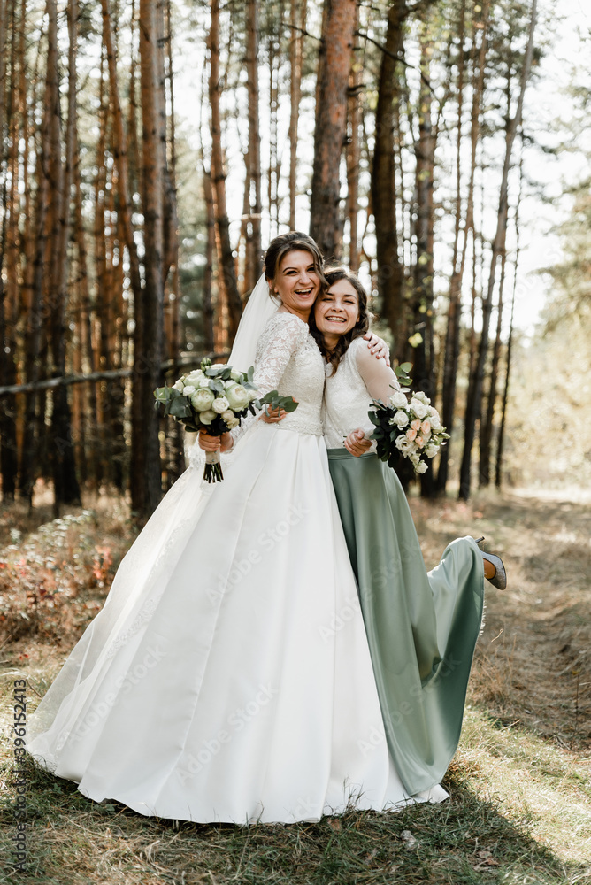 Tender bride with smiling bridesmaids dressed in long elegant dresses,bridesmaids with happy bride on wedding day. wedding bouquets are held by girlfriends, wedding day,