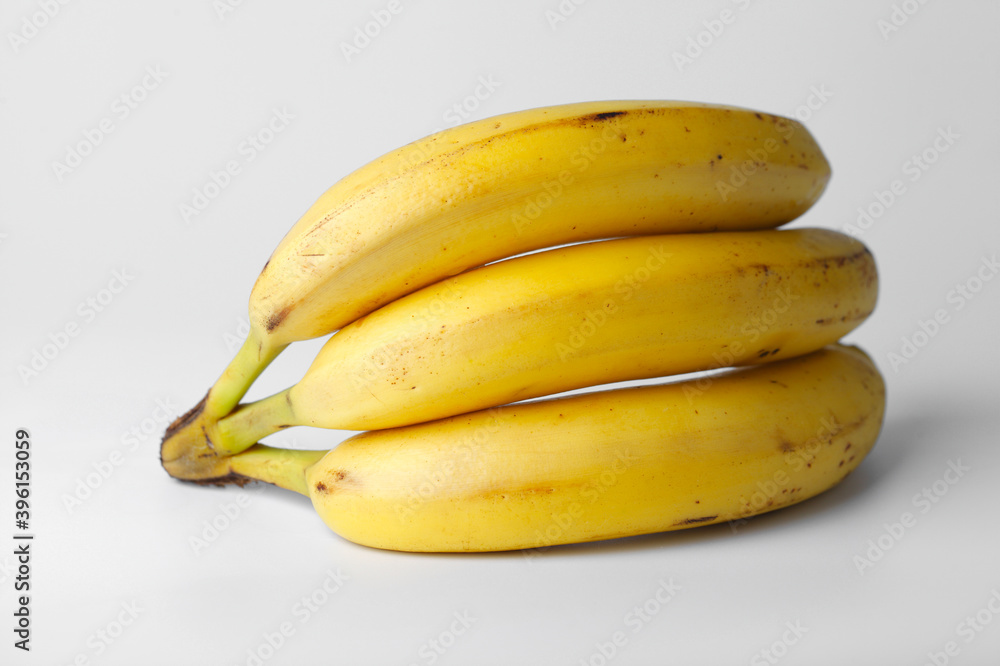 Three yellow bananas close up on a white background