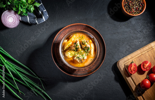 Beef stewed with vegetables( potatoes, carrots, tomatoes, onions) in a clay pot on dark background photo