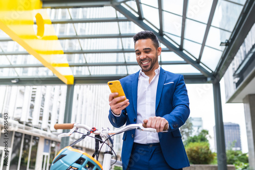 Young Businessman Using Cellphone While Walking Holding his Bike. photo