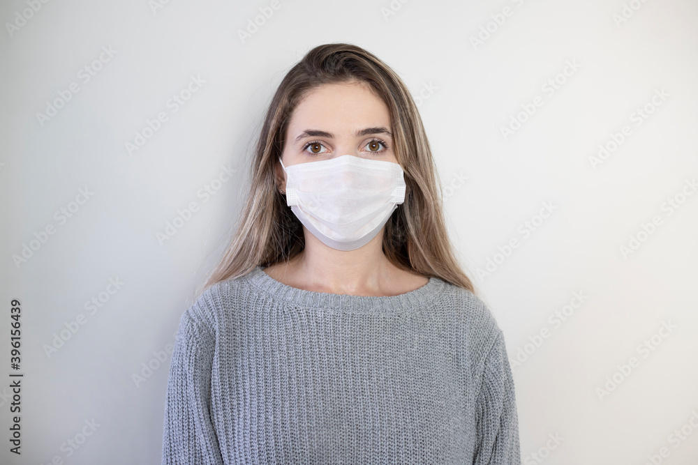 Portrait of a young girl in a medical mask isolated on a white wall background. Young woman patient, copy space Portrait of a young girl in a medical mask isolated on a white wall background. Young woman patient, copy space