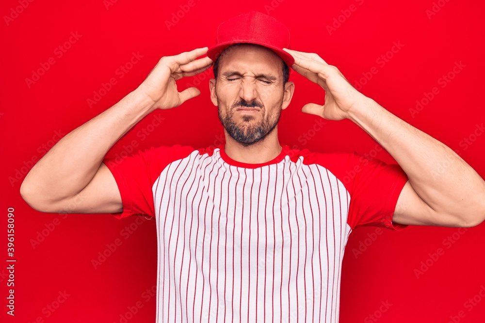 Young handsome player man wearing baseball sportswear over isolated red background with hand on head, headache because stress. Suffering migraine.