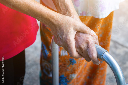 Asian old woman standing with her hands on a walker with daughter's hand,Hand of old woman holding a staff cane for helping walking