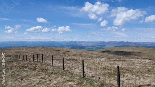 fence between pastures on top of Scottish hills on a hot summer day