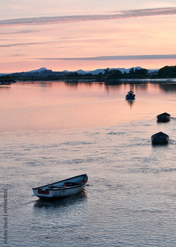 Naklejka premium Fishing boats on river Forth during sunset in Alloa harbour overlooking Stirling Castle and Scottish hills 