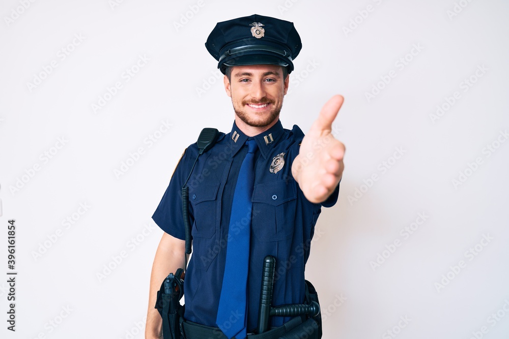 Young caucasian man wearing police uniform smiling friendly offering handshake as greeting and welcoming. successful business. Young caucasian man wearing police uniform smiling friendly offering handshake as greeting and welcoming. successful business.