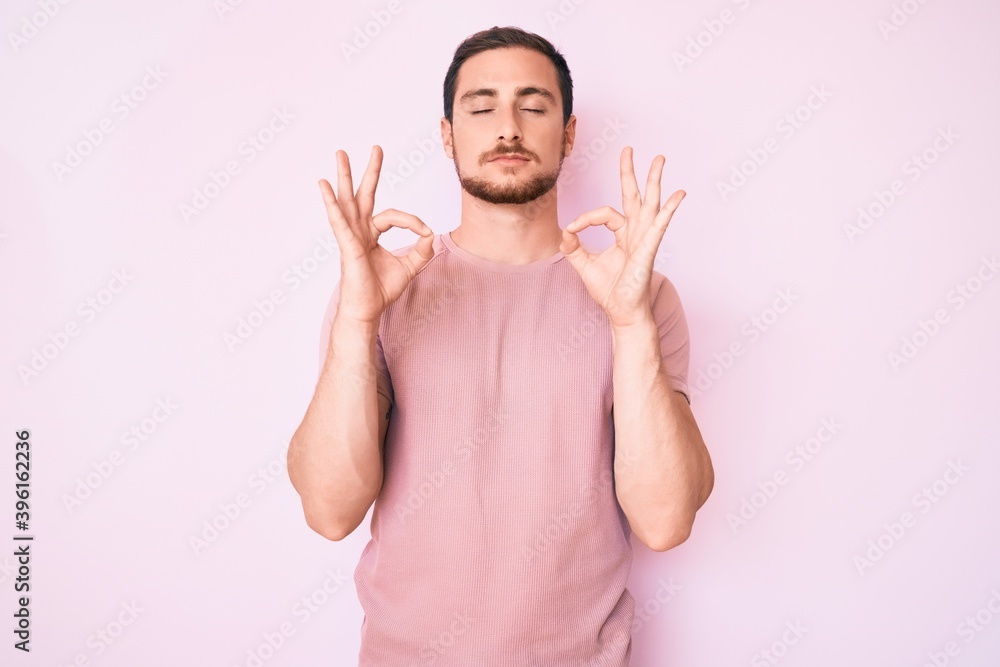 Naklejka premium Young handsome man wearing casual tshirt relax and smiling with eyes closed doing meditation gesture with fingers. yoga concept.