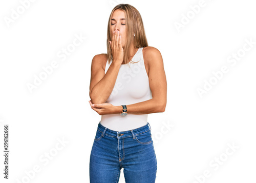 Young blonde woman wearing casual style with sleeveless shirt bored yawning tired covering mouth with hand. restless and sleepiness. © Krakenimages.com