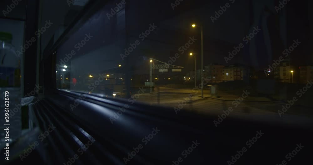 looking out the window of a train, it's night, the many lights brighten the darkness up, coloring the scenery looking out the window of a train, it's night, the many lights brighten the darkness up, coloring the scenery