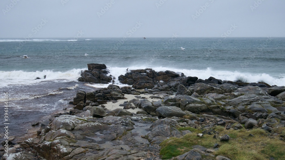 Angry ocean waves crushing against stone Scottish shore on a very windy day on the Isle of Barra