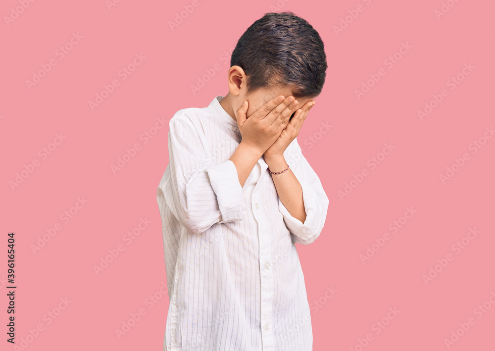 Cute blond kid wearing elegant shirt with sad expression covering face with hands while crying. depression concept. Cute blond kid wearing elegant shirt with sad expression covering face with hands while crying. depression concept.
