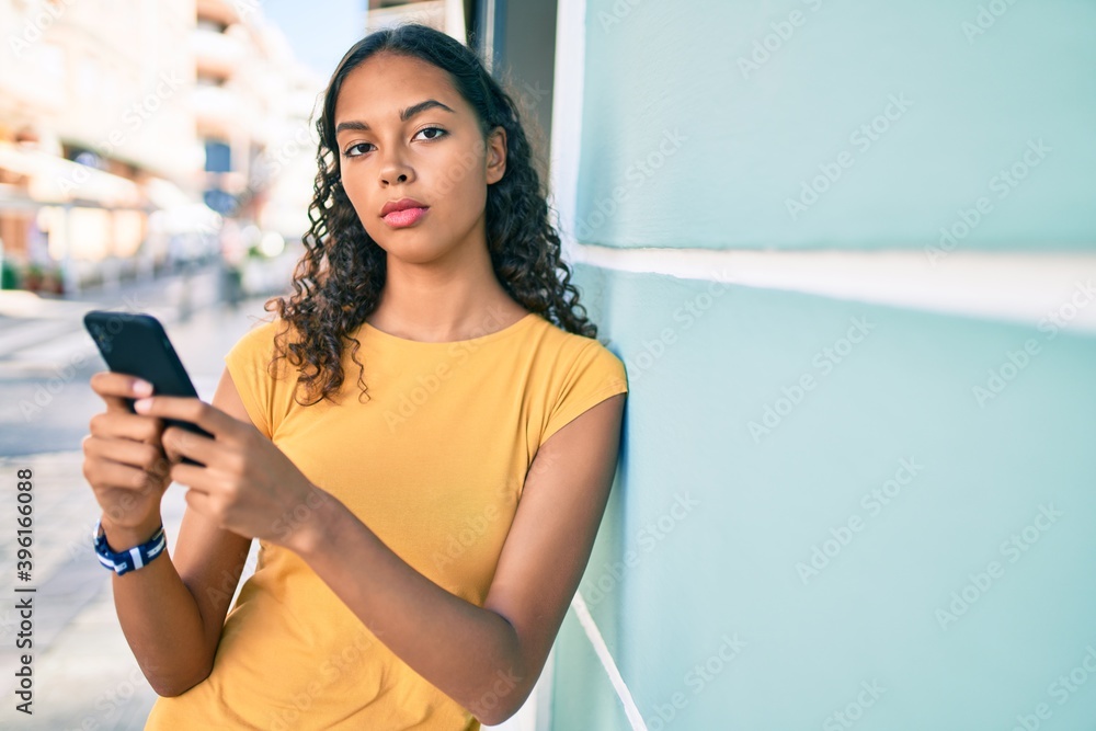 Young african american girl with unhappy expression using smartphone at city.