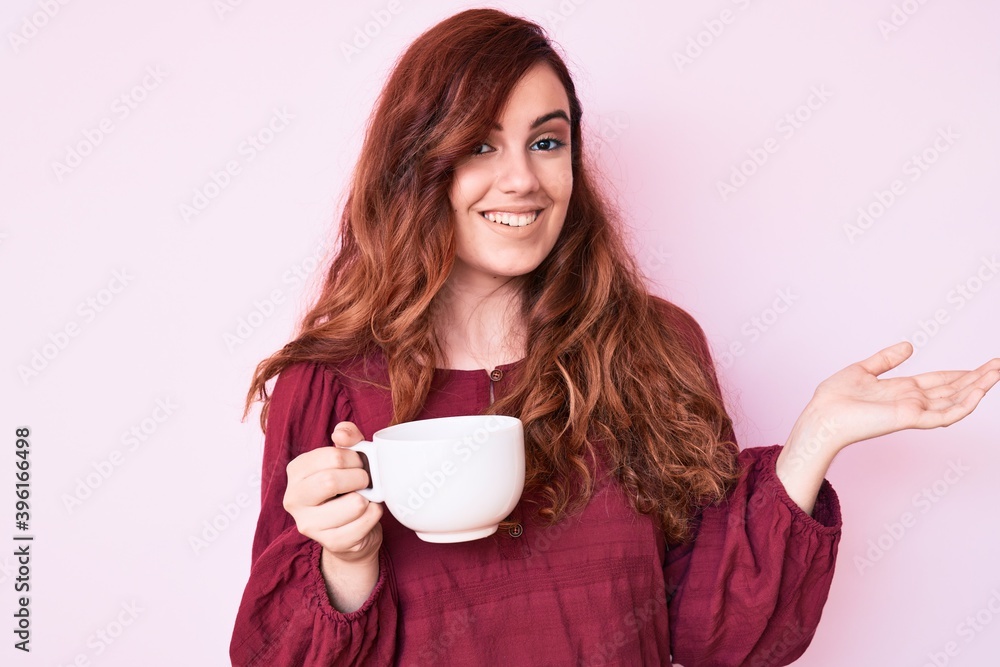 Young beautiful woman holding coffee celebrating achievement with happy smile and winner expression with raised hand Young beautiful woman holding coffee celebrating achievement with happy smile and winner expression with raised hand