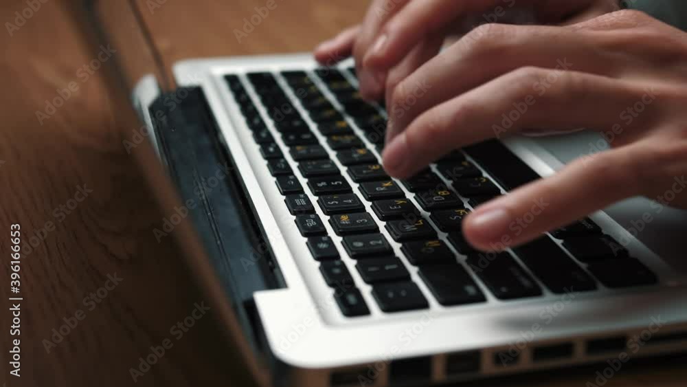Close up man hands typing on laptop keyboard sitting at the table at home or office Close up man hands typing on laptop keyboard sitting at the table at home or office