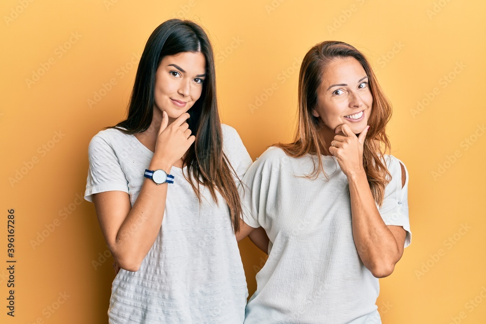 Hispanic family of mother and daughter wearing casual white tshirt looking confident at the camera smiling with crossed arms and hand raised on chin. thinking positive. Hispanic family of mother and daughter wearing casual white tshirt looking confident at the camera smiling with crossed arms and hand raised on chin. thinking positive.