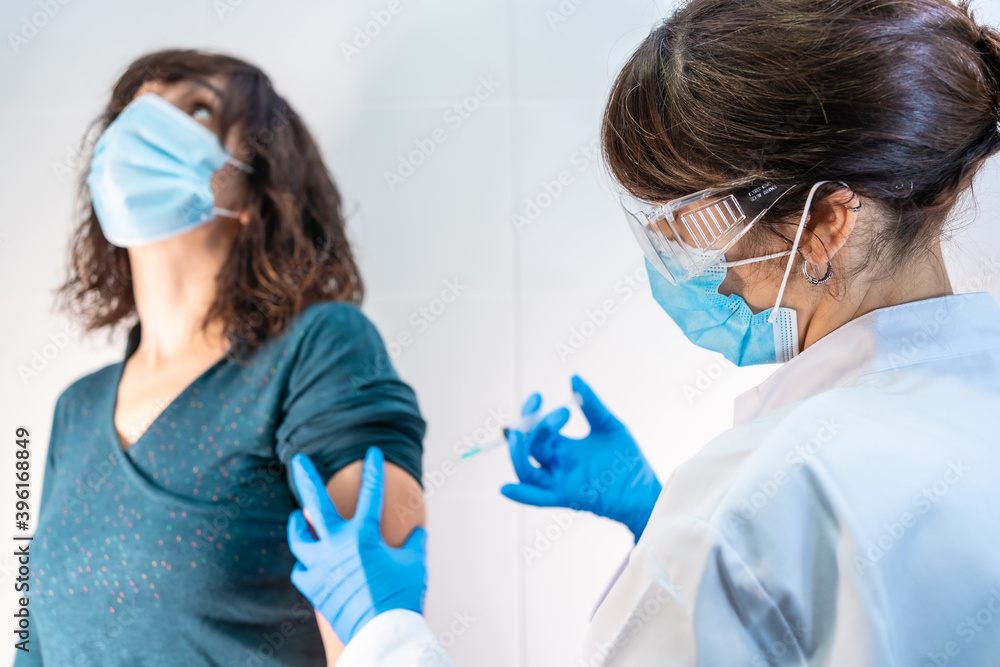 Coronavirus vaccine applied to a young woman by a doctor. Antibodies, immunize population. side effects, risk people, antibodies, new normal, covid-19. Coronavirus vaccine applied to a young woman by a doctor. Antibodies, immunize population. side effects, risk people, antibodies, new normal, covid-19.