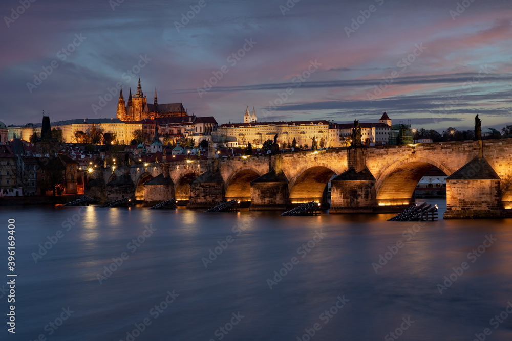 view of the illuminated Charles Bridge and Prague Castle and St. Vitus Cathedral in the center of Prague after sunset