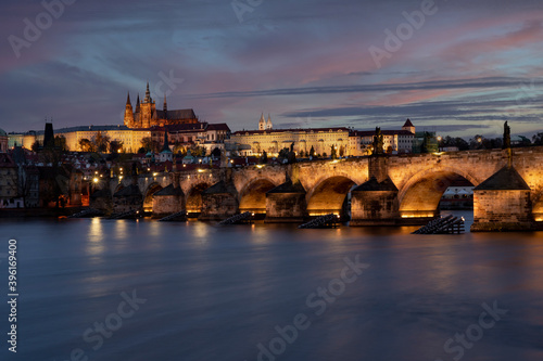view of the illuminated Charles Bridge and Prague Castle and St. Vitus Cathedral in the center of Prague after sunset © svetjekolem