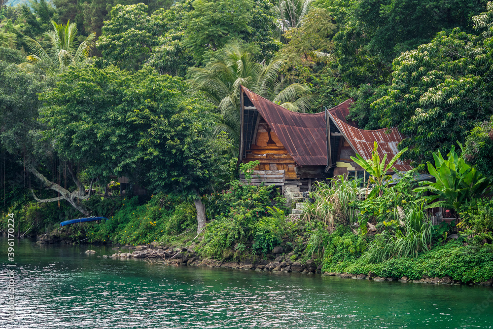 Batak ethnic house, hidden between lush forests and Lake Toba. Tuktuk, Tobasa Regency, North Sumatra, Indonesia. November 2020 Batak ethnic house, hidden between lush forests and Lake Toba. Tuktuk, Tobasa Regency, North Sumatra, Indonesia. November 2020