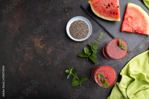 Watermelon juice with chia seeds and mint in glass on a black concrete background with green textile. Top view,  copy space.