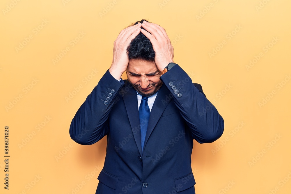 Young hispanic man wearing suit suffering from headache desperate and stressed because pain and migraine. hands on head. Young hispanic man wearing suit suffering from headache desperate and stressed because pain and migraine. hands on head.