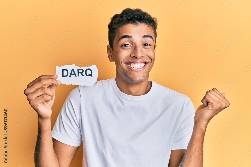 Young handsome african american man holding darq technologies word screaming proud, celebrating victory and success very excited with raised arm Young handsome african american man holding darq technologies word screaming proud, celebrating victory and success very excited with raised arm