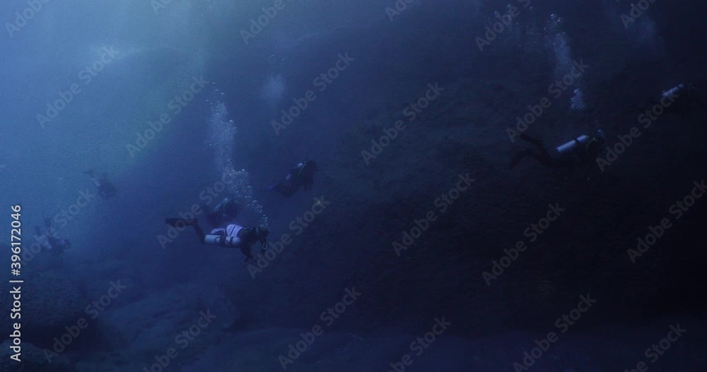 scuba divers exploring the reefs and underwater with rocks ocean scenery
