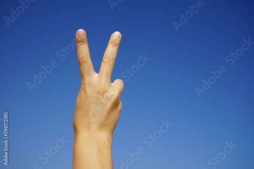 women's hands show the number two against a cloudless blue sky © Natalia Tarasova