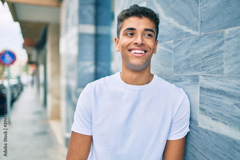 Young latin man smiling happy leaning on the wall at the city. Young latin man smiling happy leaning on the wall at the city.