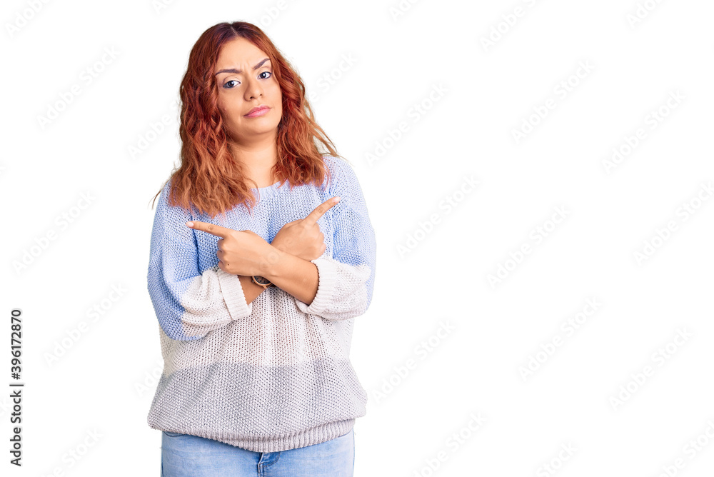 Young latin woman wearing casual clothes pointing to both sides with fingers, different direction disagree Young latin woman wearing casual clothes pointing to both sides with fingers, different direction disagree