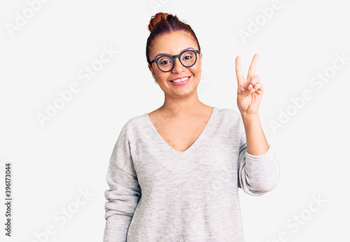 Young latin woman wearing casual clothes showing and pointing up with fingers number two while smiling confident and happy.