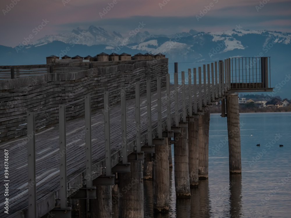 Obraz premium Stunning views of the historic wood bridge (Holzsteg) crossing the Zurich Lake with the Santis mountain peak in the background, Switzerland