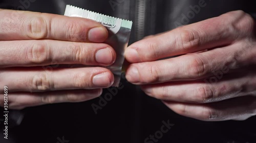 Man is opening condom. Close-up view on hands.