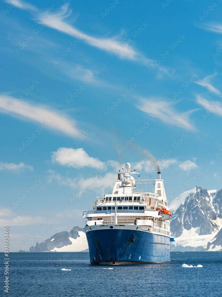 facade of cruise vessel under blue sky in front of mountains in Antarctic peninsula with copy space