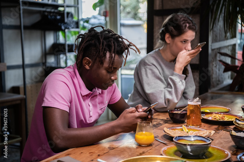 Cropped shot of a group of friends having a breakfast in the common kitchen. Gadget addiction concept.
